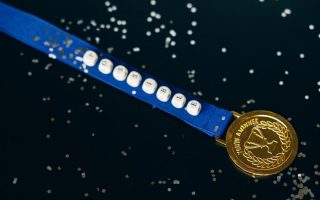 Close-up of a gold medal on a blue ribbon with 'possible' beading, symbolizing achievement.